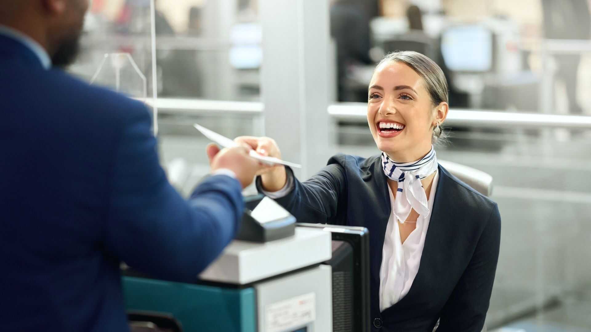 Agent d'enregistrement aéroportuaire remettant les cartes d'embarquement à des passagers au comptoir dédié d'un vol affrété en groupe.